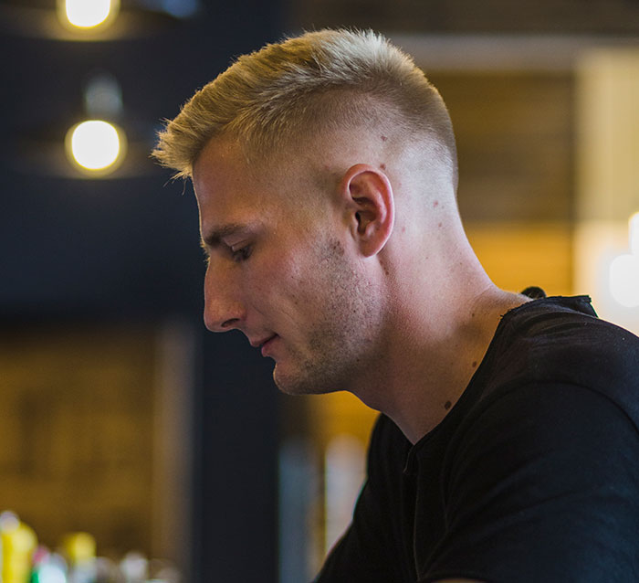 Young man reflecting thoughtfully indoors, representing reverse culture shocks experienced by Americans after moving back home.