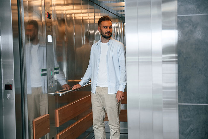 Man standing in elevator with reflective walls, symbolizing reverse culture shocks experienced by Americans moving back home.