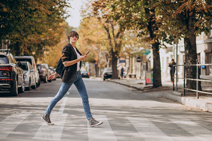 Young woman crossing street in autumn, symbolizing Americans experiencing reverse culture shocks after moving back home.