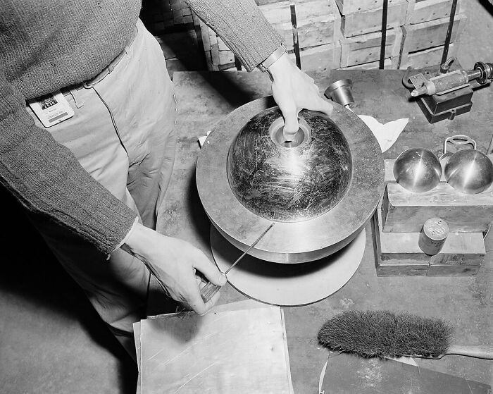 Person examining a spherical metal object in a workshop setting, showcasing one of the biggest world unexpected discoveries.