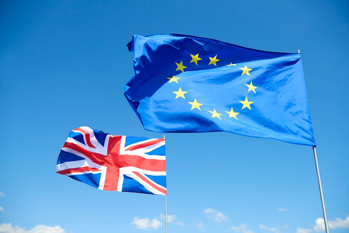 European Union and United Kingdom flags flying against a clear sky representing biggest world unexpected discoveries.