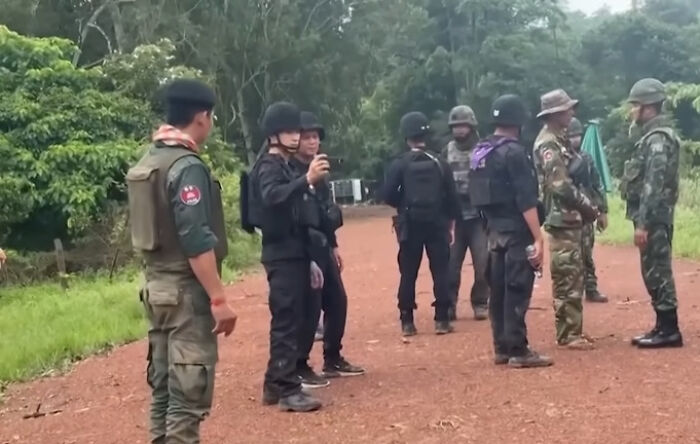Group of armed personnel in tactical gear standing on a dirt path surrounded by greenery during biggest world unexpected discoveries mission.