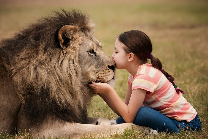 Young girl gently kissing a large lion in a grassy field, showcasing one of the biggest world unexpected discoveries.