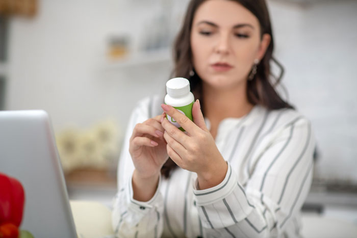 Woman holding a pill bottle thoughtfully, representing control over decisions about wife's body in a personal setting. Woman holding a pill bottle thoughtfully, representing control over decisions about wife's body in a personal setting.