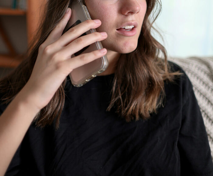 Young woman with long hair in black shirt holding a phone to her ear, reflecting the intensity of Reddit not for the faint of heart.