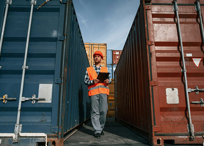 Blue collar worker in safety gear inspecting cargo containers at a job site, highlighting scary experiences on site.
