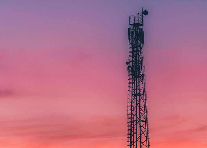 Communication tower at a job site against a colorful sunset sky, illustrating blue collar workers' scariest experiences.