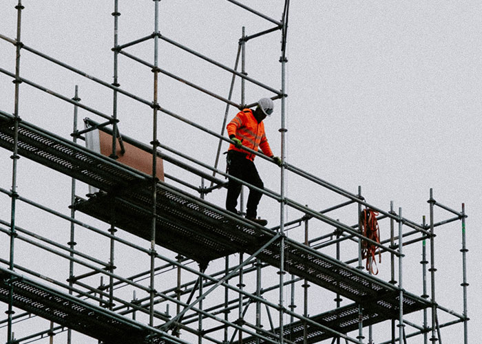 Construction worker in safety gear navigating scaffolding, illustrating blue collar workers' scariest job site experiences.