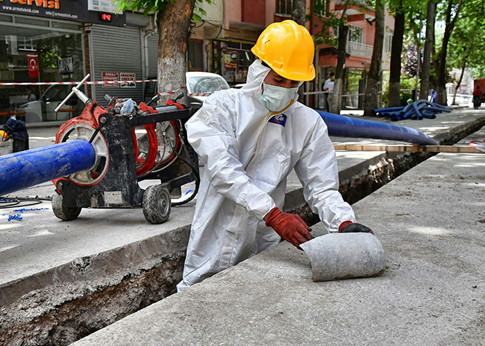 Construction worker in protective gear and helmet handling concrete near an open trench on a job site safety hazard.