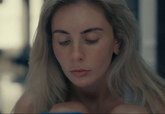 Woman with blonde hair looking down with a serious expression, body language expert decodes subtle emotional change. - 6