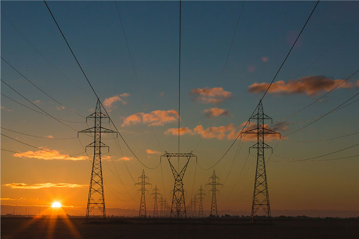 Electricity transmission towers at sunset, illustrating the profitability of key industries in modern economy.