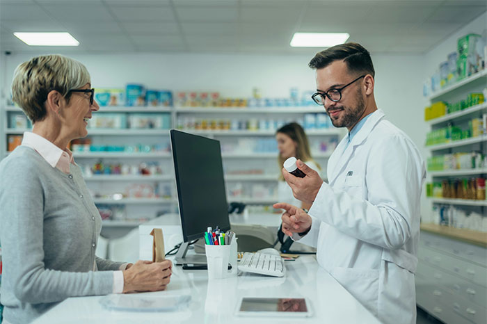 Pharmacist consulting with a customer in a drugstore, highlighting profitable industries in healthcare and retail sectors.