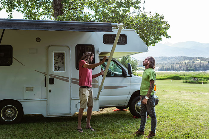 Two men setting up an awning on a recreational vehicle, illustrating profitable industries in outdoor and travel sectors.