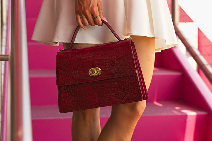 Close-up of a person holding a stylish red handbag, highlighting profitable fashion industry trends today.
