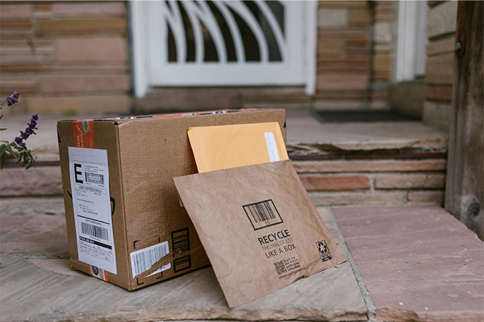 Packages and envelopes left on a doorstep, illustrating profitable industries in shipping and delivery services today.