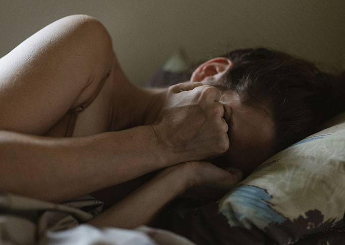 Woman lying in bed covering face, experiencing heartbreak and emotional pain after mother&rsquo;s death reveals boyfriend&rsquo;s true character.