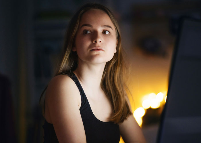 Young woman faces double heartbreak, reflecting on loss and boyfriend&rsquo;s true character in a dimly lit room.