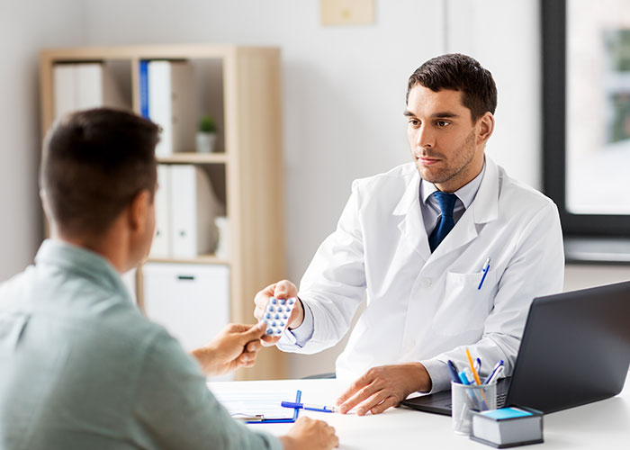 Doctor handing a patient medication in a clinical office, relating to cancer and HPV health concerns discussion.