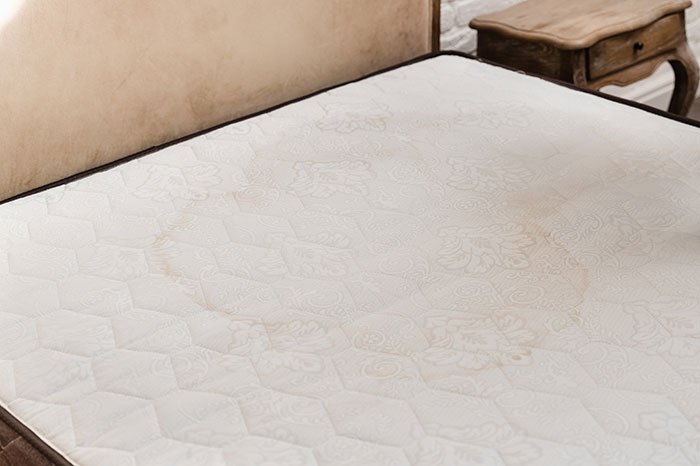 Mattress with a visible bedwetting stain, highlighting the issue of man wetting the bed and not seeing it as a problem.