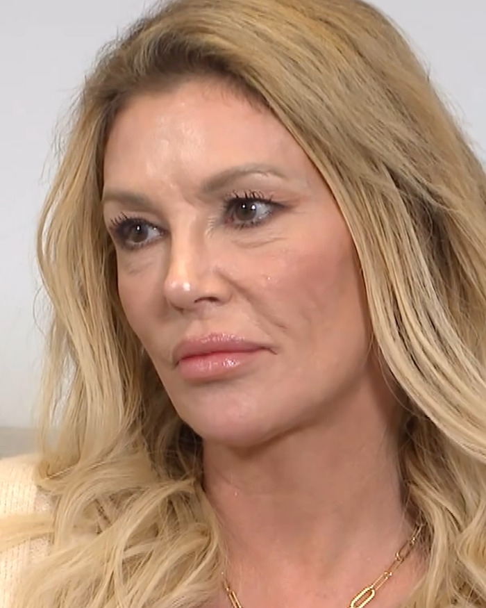 Brandi Glanville with long blonde hair and neutral makeup, appearing serious during an indoor interview session