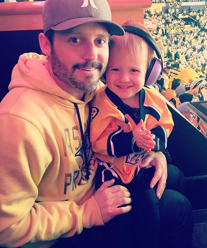 Man and child wearing Nashville Predators gear at a hockey game, reflecting Kelly Clarkson’s pain following ex’s passing. Man and child wearing Nashville Predators gear at a hockey game, reflecting Kelly Clarkson’s pain following ex’s passing.