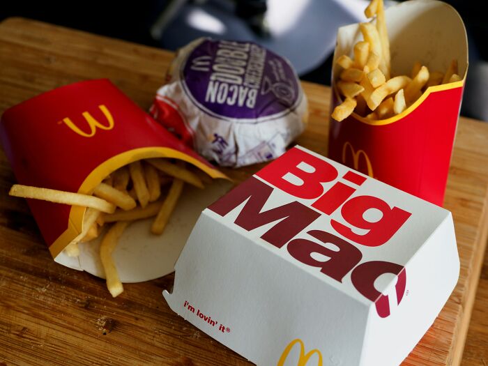 McDonald's Big Mac burger with two servings of French fries on a wooden surface representing shopping cravings.