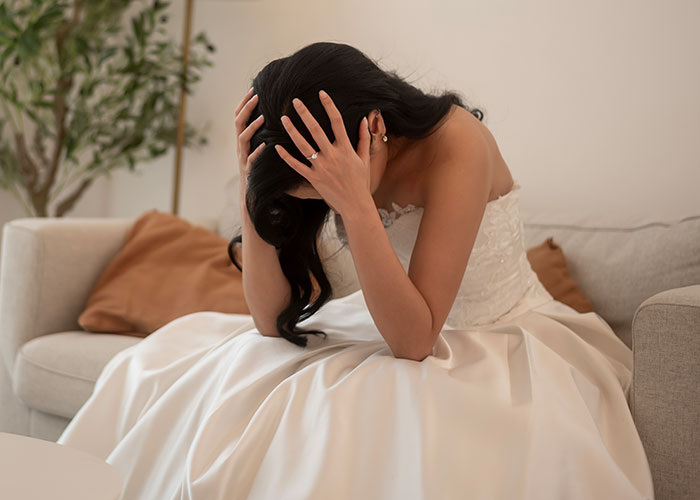Bride in wedding dress sitting on sofa distressed after pet pig ruins wedding, mother humiliated in front of guests