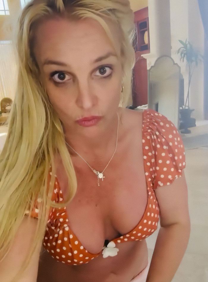Britney Spears wearing a polka dot top and necklace, showing off her figure indoors, raising mental health concerns.