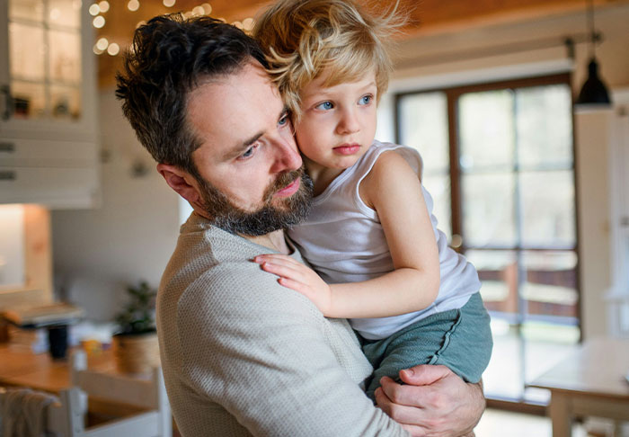 Man holding child indoors, illustrating a guy accusing sister of being a stranger to his kids after refusing childcare.