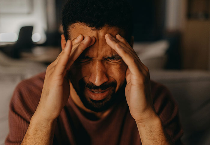 Man stressed and holding head in hands, illustrating conflict over sister refusing childcare duties and being stranger to kids.