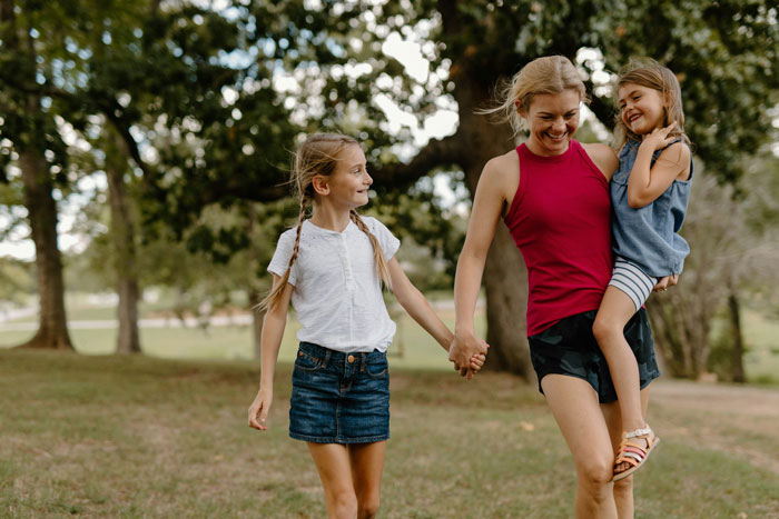 Woman enjoying time with her children outdoors, highlighting postpartum challenges and family dynamics with triplets. Woman enjoying time with her children outdoors, highlighting postpartum challenges and family dynamics with triplets.