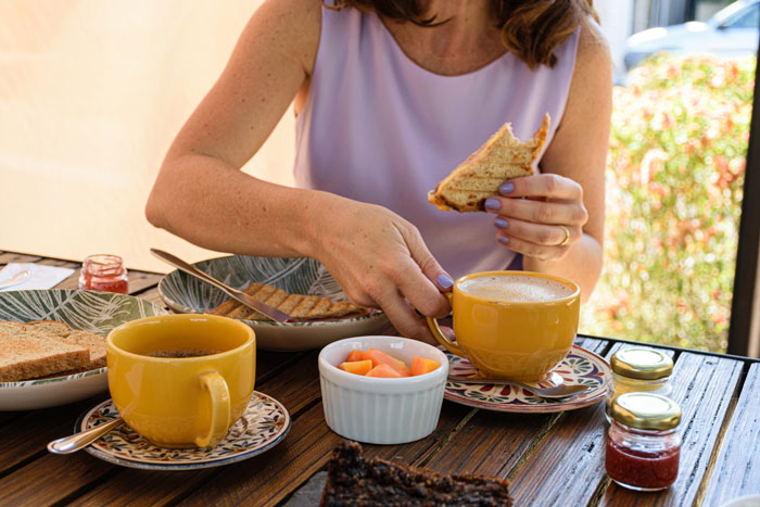 Woman enjoying brunch with coffee and toast outdoors, highlighting prioritizing brunch date over dad’s surgery decision. Woman enjoying brunch with coffee and toast outdoors, highlighting prioritizing brunch date over dad’s surgery decision.