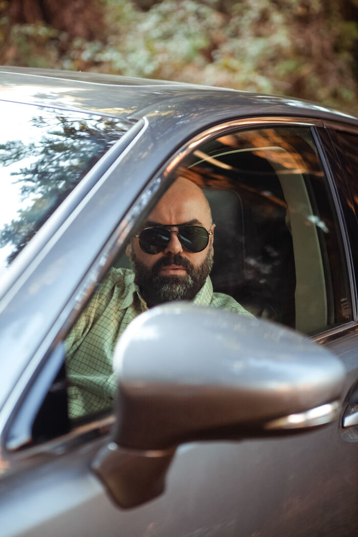 Man wearing sunglasses sitting in car, looking serious and alert after spending time in the woods, still scares me feeling. - 19