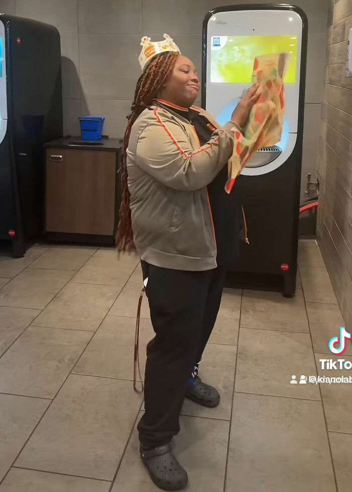 Burger King employee wearing crown, holding a pizza box, sharing emotional life update after viral performance.