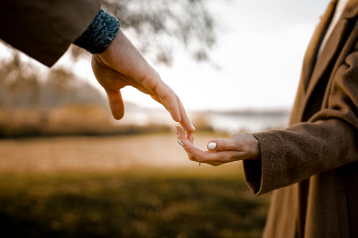 Hands of a widow and her late husband's first wife reaching out, symbolizing family ties and stepkids feeling hurt.