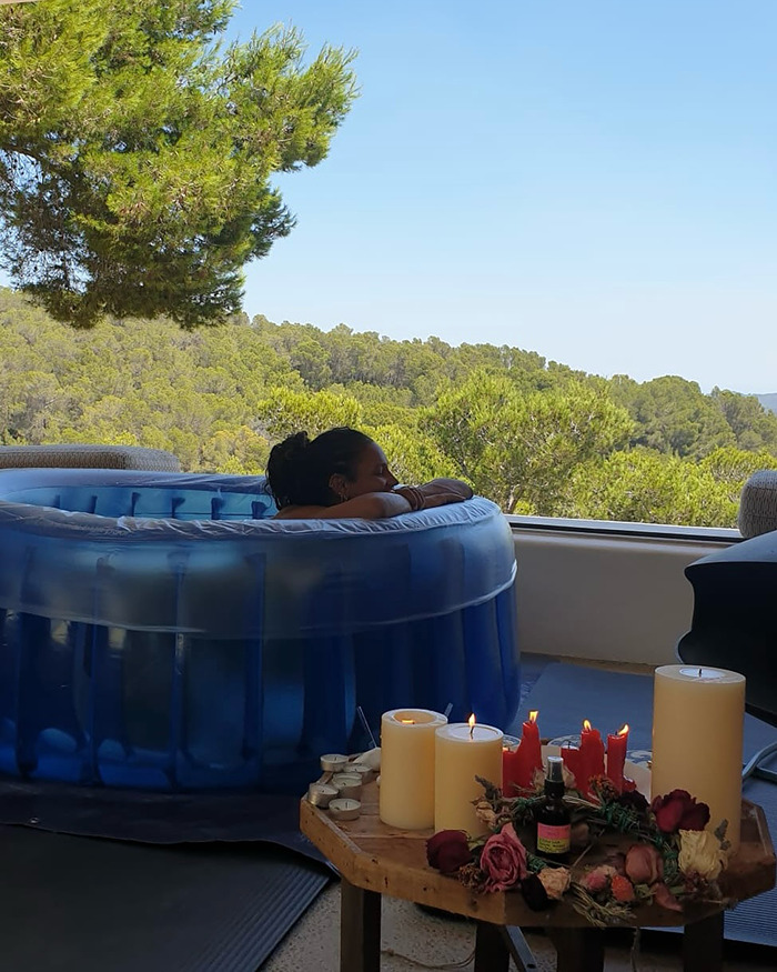 Person relaxing in an inflatable birthing pool with candles and flowers nearby, related to placenta encapsulation process. - 2