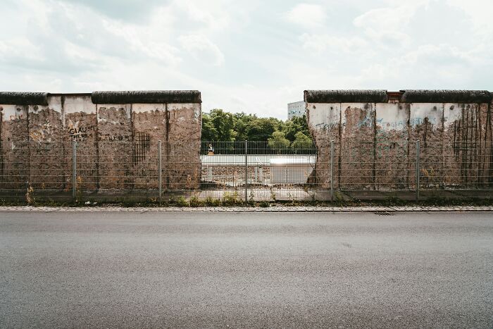 Sections of the Berlin Wall with worn graffiti and a gap, symbolizing tiny human mistakes that changed history forever.