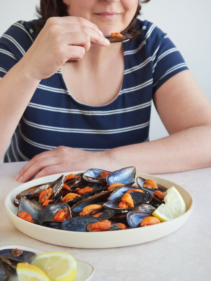 Person tasting mussels from a plate, a moment restaurant workers often keep a straight face during unusual orders.