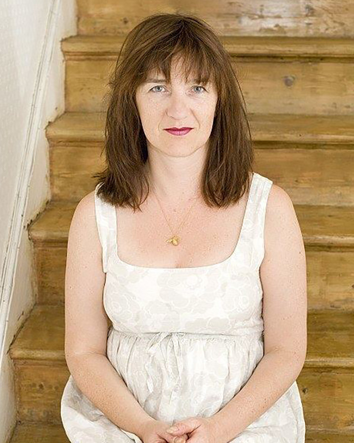 Woman sitting on wooden stairs, wearing a white dress, representing columnist in discussion on Sacha Baron Cohen Marvel body. - 1