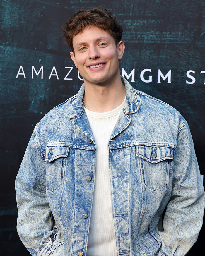 Matt Rife wearing a denim jacket and white shirt, smiling at an event with Amazon MGM Studios backdrop.