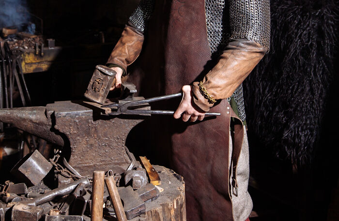 Blacksmith working at an anvil, holding hammer and tongs, illustrating concept time facts about traditional craftsmanship.
