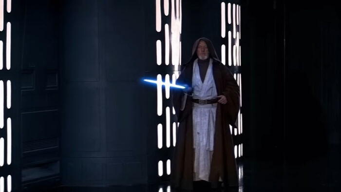 A Jedi in robes holding a blue lightsaber in a dark sci-fi hallway, symbolizing concept time facts.