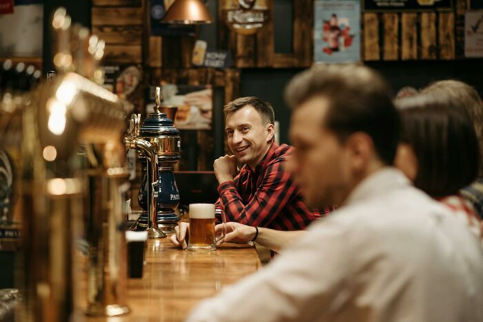 Group of friends at a bar enjoying drinks while discussing concept time facts in a cozy pub atmosphere.