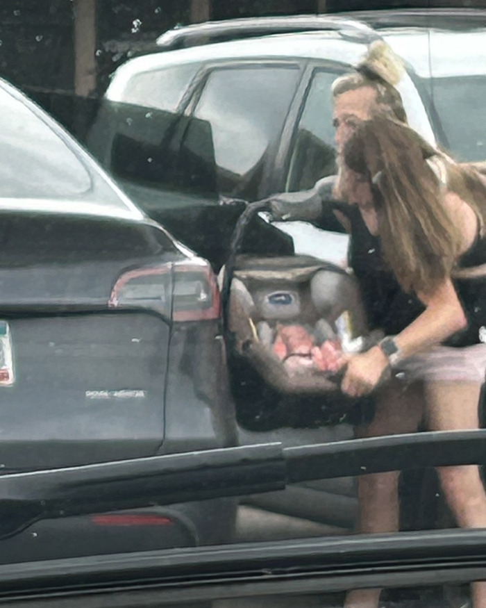 Two women outside a car, one holding a baby carrier, sparking speculation about Hensel twins motherhood and marriage. Two women outside a car, one holding a baby carrier, sparking speculation about Hensel twins motherhood and marriage.