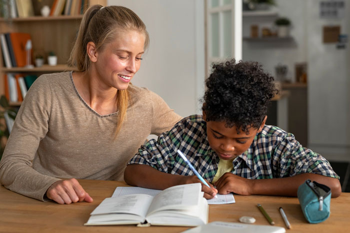 Teacher helping student with homework during unconscious bias training, highlighting issues of racist thoughts in education.