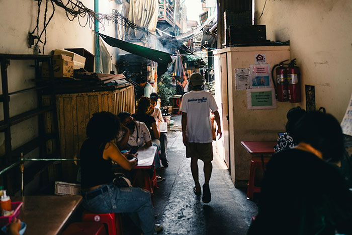 People sitting in a narrow alley cafe shaded by tarps, illustrating times conspiracy theorists were actually right.