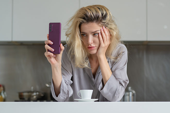 Young woman with blonde hair holding a phone looking thoughtful, reflecting on hot take opinions about boomers.