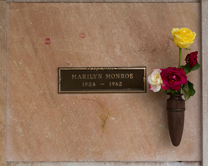 Marilyn Monroe grave plaque with roses and lipstick marks, related to autopsy and suspicious coroner findings decades later. - 8