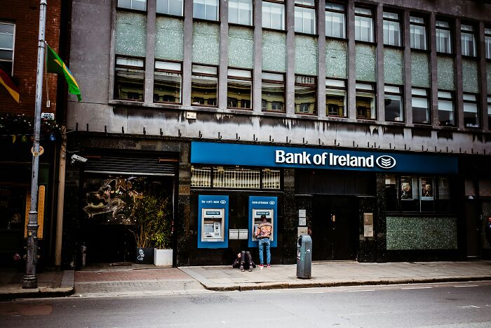 People at a Bank of Ireland ATM discovering mob money secrets after someone passed in an urban setting.