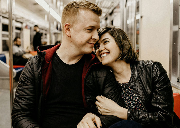 Couple sharing a tender moment on a subway, illustrating the ups and downs of having a partner who went from rags to riches.